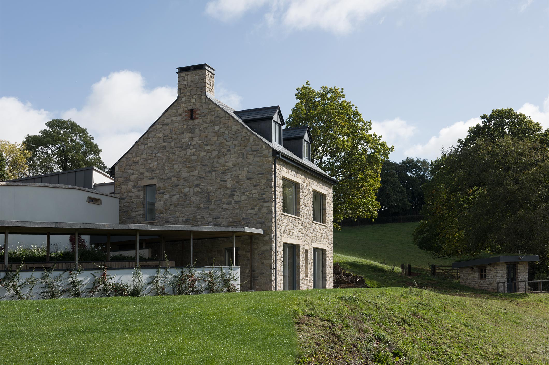 While the farmhouse stands out the extensions merge into the surrounding hillside